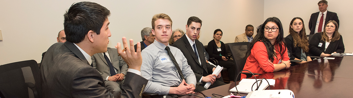 students sit in a boardroom in a meeting