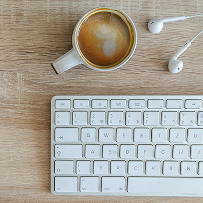 computer keyboard, coffee, and headphones on a table