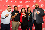 Five individual standing behind a red CSUN wall