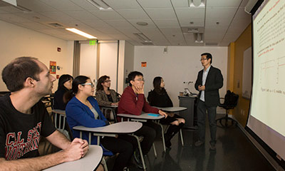 Graduate students in a classroom listening to a professor