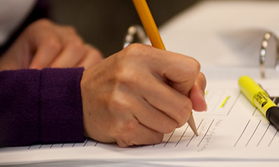 a hand holding a pencil writing on paper.
